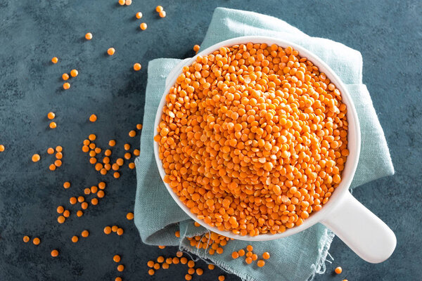 Сырая чечевица в миске на столе. Свежая чечевица. Вегетарианская еда. Вид сверху
 