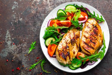 Izgara tavuk göğsü. Kızarmış tavuk fileto ve taze sebze salatası domates, salatalık ve roka yaprakları. Salatalı tavuk eti. Sağlıklı yiyecekler. Düz yatıyordu. Üst Manzara. Koyu arkaplan