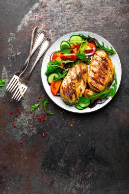 Izgara tavuk göğsü. Kızarmış tavuk fileto ve taze sebze salatası domates, salatalık ve roka yaprakları. Salatalı tavuk eti. Sağlıklı yiyecekler. Düz yatıyordu. Üst Manzara. Koyu arkaplan