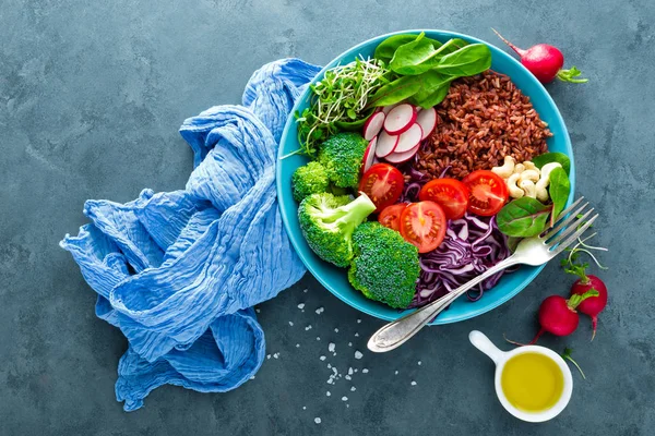 Buddha bowl meal with kale, spinach and chard leaves, brown rice, tomato, broccoli, radish, fresh green sprouts and pine nuts. Healthy balanced nutrition. Vegetarian food. Overhead view