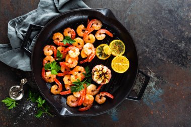 Karides ızgara tava limon ve sarımsak ile kavrulmuş. Izgara karides, karides. Deniz ürünleri. Üstten Görünüm. Koyu arka plan