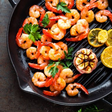 Karides ızgara tava limon ve sarımsak ile kavrulmuş. Izgara karides, karides. Deniz ürünleri. Üstten Görünüm. Koyu arka plan