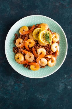 Karides ızgara kavrulmuş ve plaka üzerinde kahverengi pirinç haşlanmış. Izgara karides, karides pirinç. Deniz ürünleri. Asya mutfağı. Üstten Görünüm. Koyu arka plan