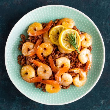 Karides ızgara kavrulmuş ve plaka üzerinde kahverengi pirinç haşlanmış. Izgara karides, karides pirinç. Deniz ürünleri. Asya mutfağı. Üstten Görünüm. Koyu arka plan