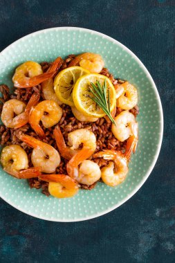 Karides ızgara kavrulmuş ve plaka üzerinde kahverengi pirinç haşlanmış. Izgara karides, karides pirinç. Deniz ürünleri. Asya mutfağı. Üstten Görünüm. Koyu arka plan