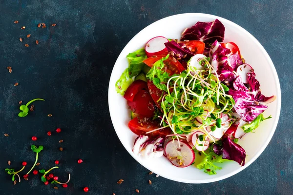 Fresh vegetable salad plate of tomatoes, italian mix, pepper, radish, green sprouts and flax seeds. Vegetarian dish, healthy food. Diet breakfast, lunch or dinner menu. Salad plate on table. Flat lay. View from above