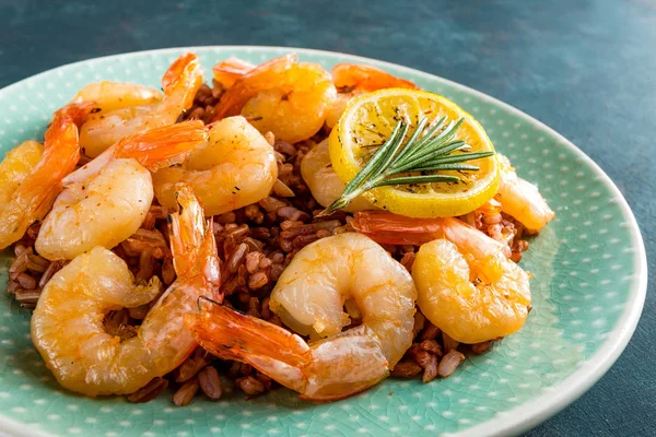 Karides ızgara kavrulmuş ve plaka üzerinde kahverengi pirinç haşlanmış. Izgara karides, karides pirinç. Deniz ürünleri. Asya mutfağı. Portre. Koyu arka plan