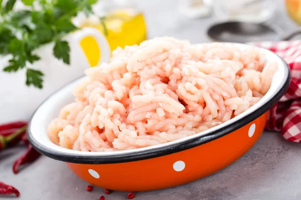 Forcemeat. Raw ground chicken meat in bowl on white kitchen table. Fresh minced chicken breast meat