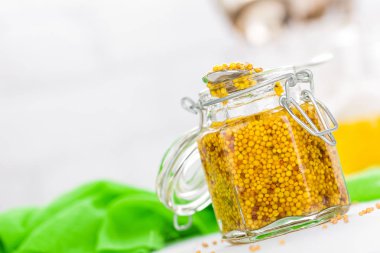 Beyaz ahşap masa portre üzerinde cam kavanoza hardal. Dijon hardalı