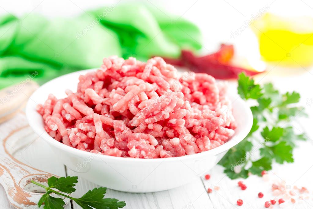 Forcemeat. Raw ground pork meat in bowl on white kitchen table. Fresh minced meat