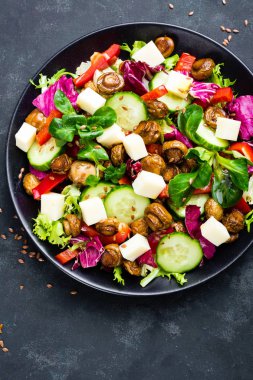 Mantar ve mozzarella peyniri siyah plaka üzerinde taze sebze salatası. Fried petrol sebze salatası ile