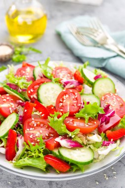 Domates, salatalık, tatlı biber ve susam ile taze sebze salatası. Beyaz tabakta sebze salatası