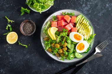 Ketogenik, paleo diyet kasesi tuzlanmış somon balığı, limon, avokado, zeytin, haşlanmış yumurta, salatalık, yeşil marul salatası ve chia tohumu, sağlıklı besin akımı, üst görünüm