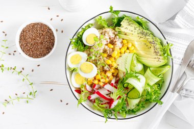 Kahvaltı yulaf lapası taze sebze salatası salatalık, turp, marul, mısır, avokado, chia tohumu ve haşlanmış yumurta. Sağlıklı dengeli yiyecekler. Üst Manzara. Düz yatıyordu