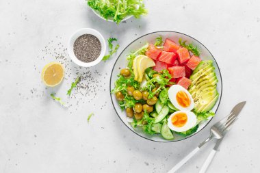 Ketogenik, keto veya tuzlanmış somon balığı, limon, avokado, zeytin, haşlanmış yumurta, salatalık, yeşil marul salatası ve chia tohumlu paleo diyet kasesi. Sağlıklı beslenme eğilimi. Üst görünüm