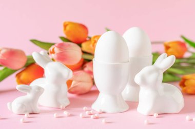 Pembe arka planda bahar çiçekleriyle Paskalya bayramı süsleri, bayram tebrik kartı.