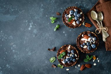 Badem, ceviz ve taze yaban mersinli çikolata kremalı sağlıklı çiğ vejetaryen tatlı tartları.