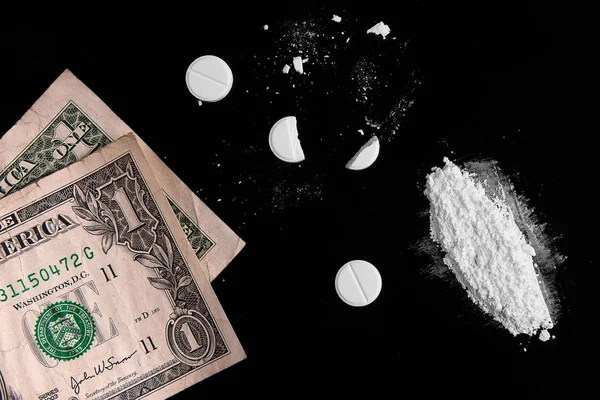 Drugs and money scattered on a black background — Stock Photo, Image