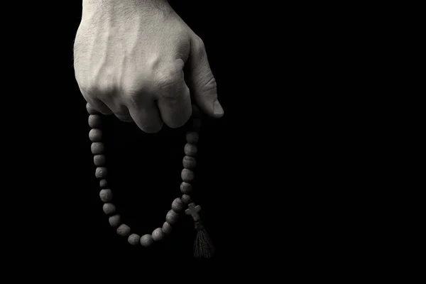 Rosenkranz in männlichen Händen auf schwarzem Hintergrund — Stockfoto