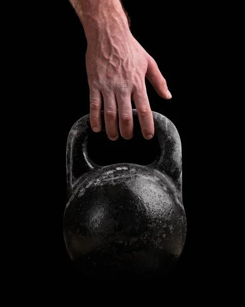 Kettlebell en la mano de un hombre sobre un fondo negro — Foto de Stock