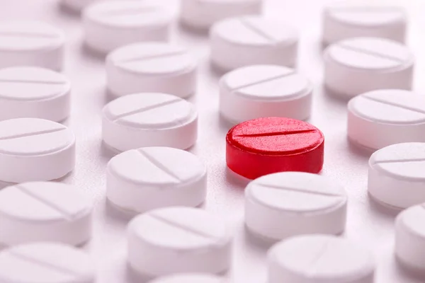 Много белых таблеток вокруг одного красного . — стоковое фото