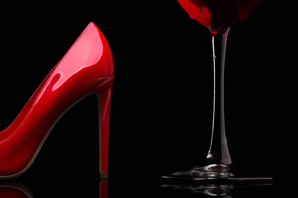 A glass of red wine and women's shoes with heels. — Stock Photo, Image