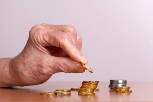 Mão de um homem idoso e uma pilha de moedas na mesa . — Fotografia de Stock