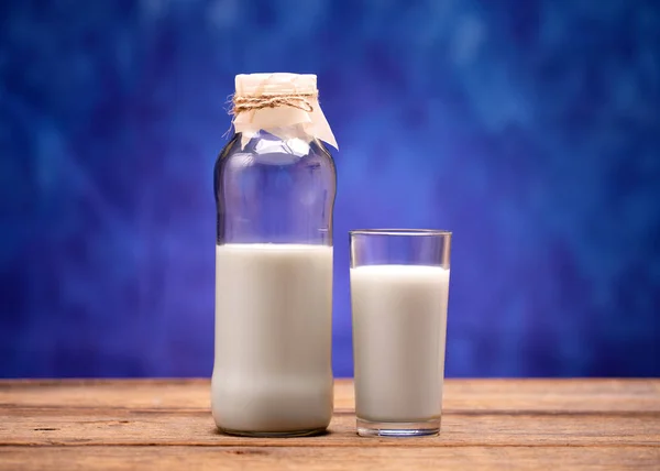 Leche en una botella de vidrio. Leche vertida en un vaso . — Foto de Stock