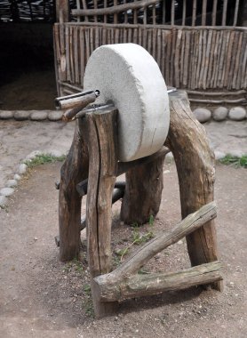 Tahta destekler üzerinde eski bir kılavuz değirmen taşı (öğütme makinesi)