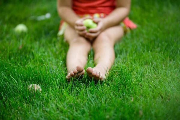 Meisje zittend op het gras met apple — Stockfoto