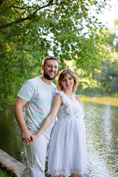 Мужчина и беременная жена стоят у озера — стоковое фото