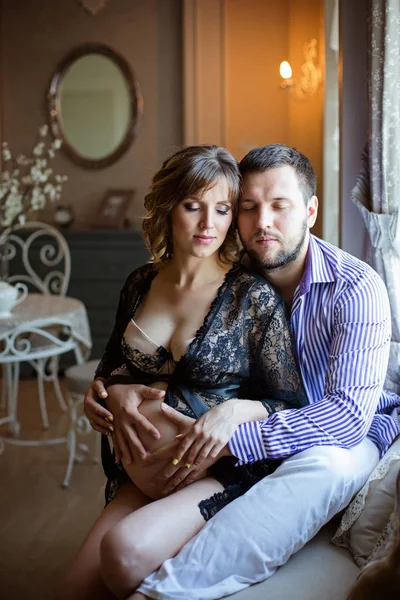 Мужчина и беременная жена сидят на диване — стоковое фото