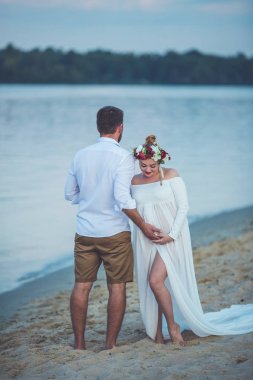 Yakışıklı delikanlı ve onun hamile eşi nehir sahilde elele 
