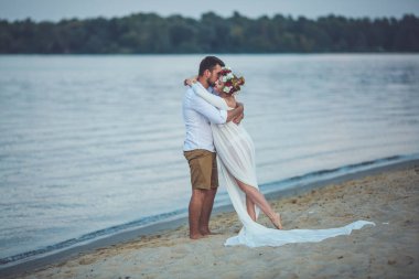 Yakışıklı delikanlı ve onun hamile eşi nehir kumsalda sarılma 