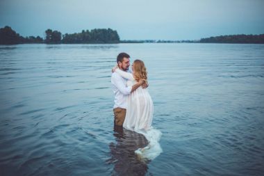 Yakışıklı delikanlı ve onun hamile eşi Gölü suda duran ve sarılma 