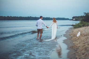 Yakışıklı delikanlı ve onun hamile eşi elele ve nehir Sahilde yürüyüş