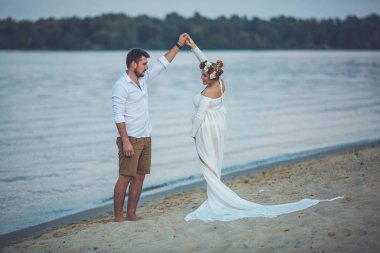 Yakışıklı delikanlı ve onun hamile eşi nehir kumsalda dans