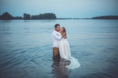 Yakışıklı delikanlı ve onun hamile eşi Gölü suda duran ve sarılma 