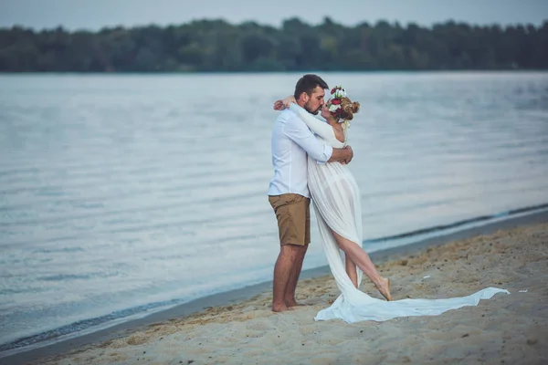 年轻英俊的男人和他怀孕的妻子在河边接吻 — 图库照片