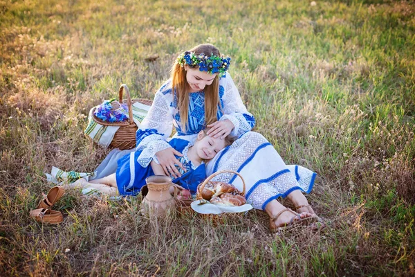 Anne ve sevimli kızı sıcak yaz gününde piknik Ukrayna Ulusal kostümleri