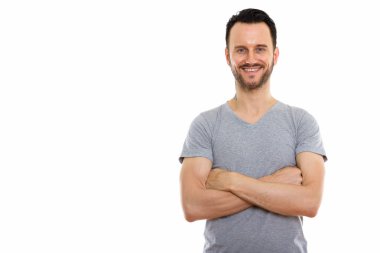 Kollarını kavuşturup gülümseyen mutlu genç adamın stüdyo fotoğrafı.
