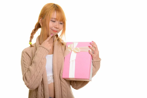 年轻可爱的亚洲女人一边拿着礼品盒一边想 — 图库照片