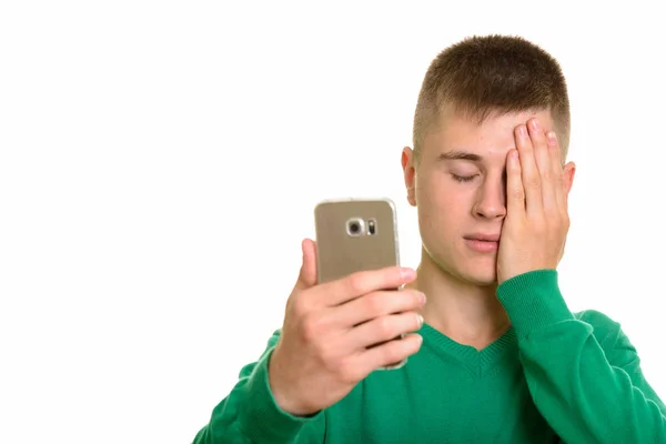 Jovem caucasiano homem segurando telefone celular olhando cansado com os olhos — Fotografia de Stock