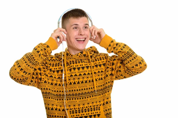 Молодой счастливый кавказский мужчина улыбается и слушает музыку в то время как т — стоковое фото