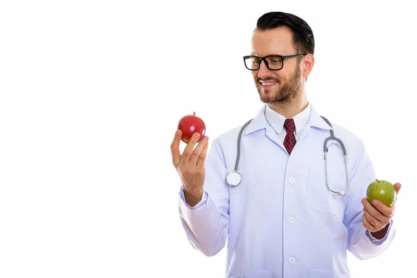 Στούντιο Πλάνο Του Χαρούμενος Νεαρός Γιατρός Χαμογελώντας Κοιτάζοντας Κόκκινο Μήλο — Φωτογραφία Αρχείου