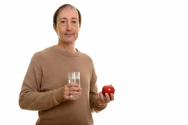 スタジオショットの成熟した男保持ガラスの水と赤リンゴ — ストック写真