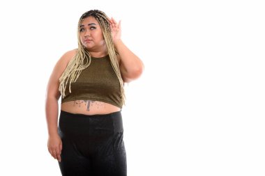 Genç şişman Asyalı kadının, dinlerken ayakta durduğu bir stüdyo fotoğrafı.