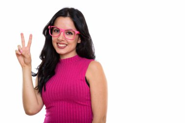 Barış işareti verirken gülümseyen genç İspanyol kadının stüdyo fotoğrafı.