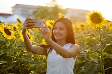 Genç mutlu Asyalı kadın ile selfie resim çekerken gülümseyen