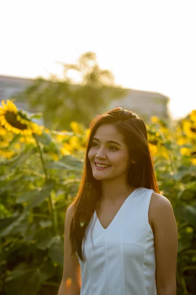 Junge glückliche asiatische Frau lächelt und denkt beim Betrachten di — Stockfoto